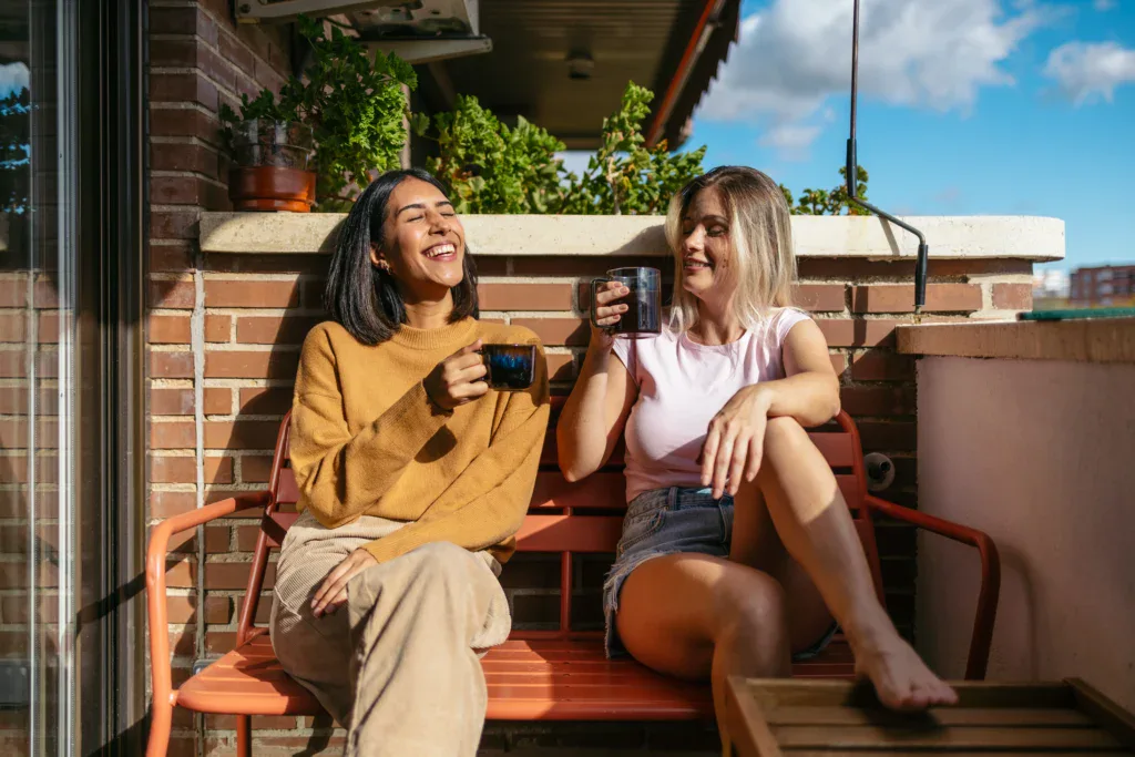 Two Women Drinking Coffee on Balcony