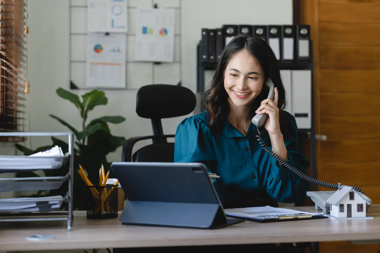 Property Manager at her desk answering the phone and on her tablet.